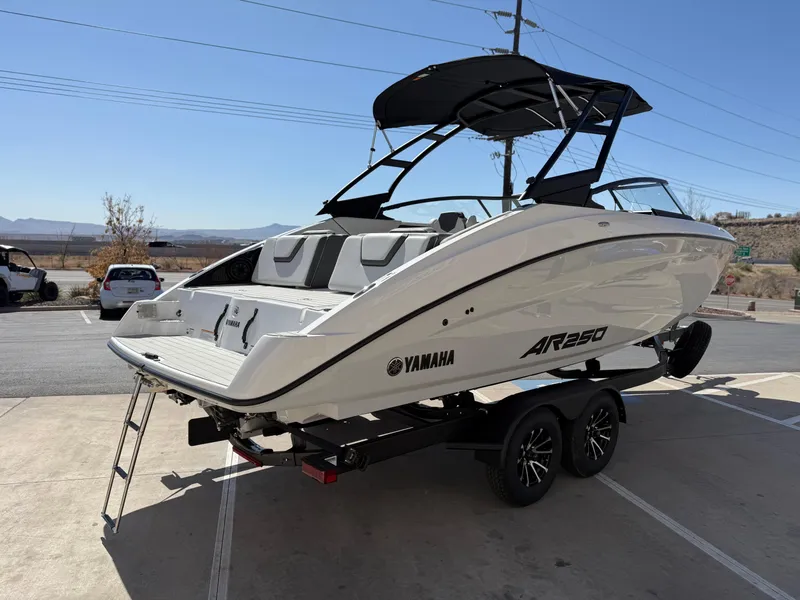 Slide: The Image of 2025 Yamaha Boats AR250 on trailer, sleek design, white exterior, parked outdoors. - 4