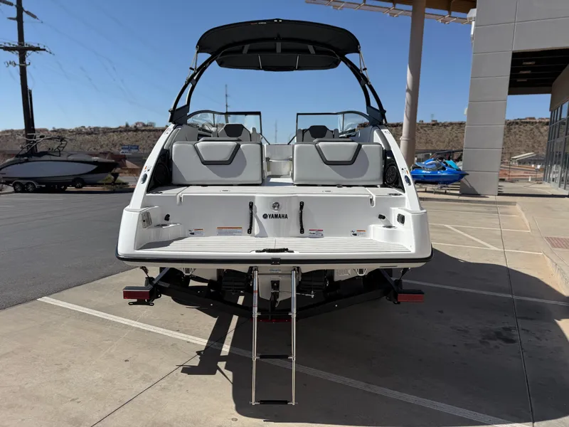 Slide: The Image of 2025 Yamaha Boats AR250, rear view, parked on concrete, showcasing swim platform and ladder. - 6