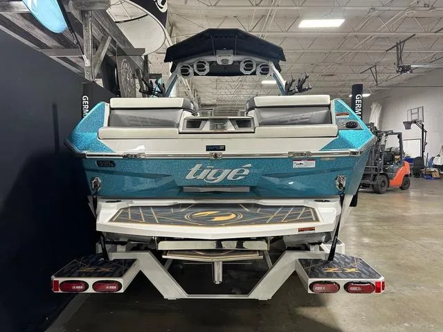 Slide: The Image of 2025 Tigé 25ZX boat in showroom, rear view, blue and white design. - 3