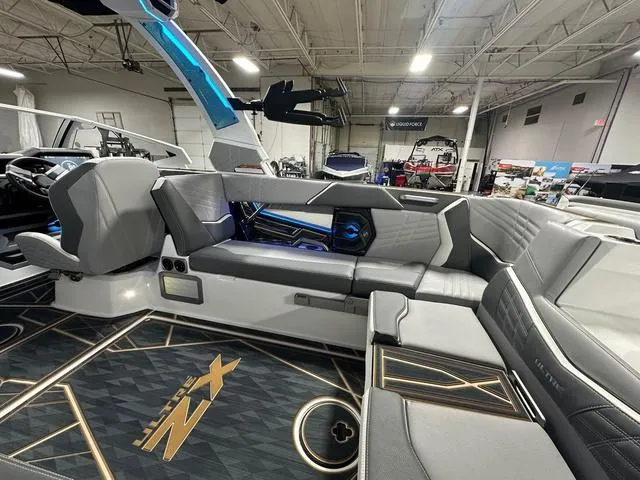 Slide: The Image of 2025 Tigé 25ZX boat interior with modern seating and sleek design in a showroom. - 8