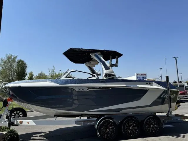 Slide: The Image of 2025 Tigé 23ZX Ultre boat on a trailer, sleek design, parked outdoors. - 3