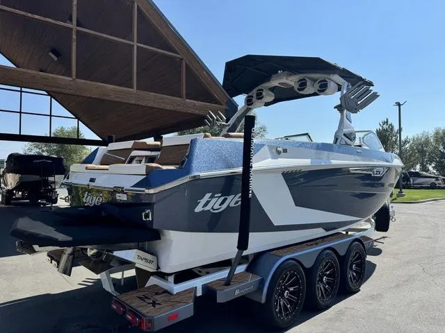 Slide: The Image of 2025 Tigé 23ZX Ultre boat on trailer, parked outdoors under a wooden structure. - 7