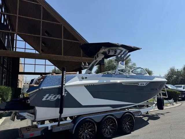 Slide: The Image of 2025 Tigé 23ZX Ultre boat on trailer, parked outdoors under clear sky. - 8