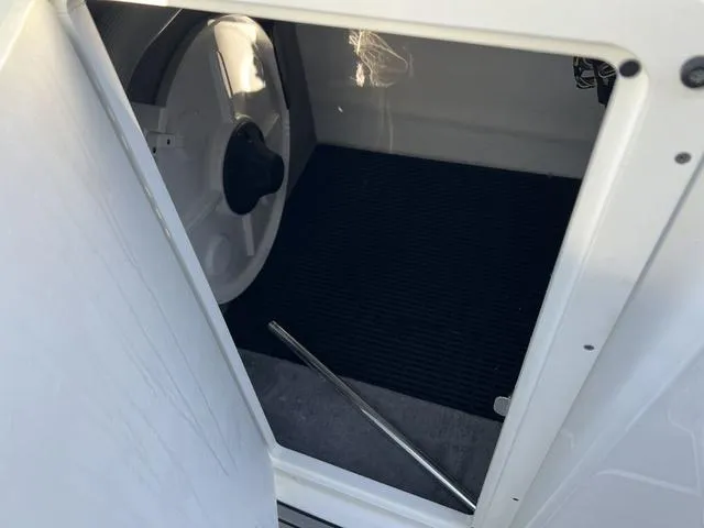 Slide: The Image of Storage compartment in a 2020 Monterey MX6 SURF boat, featuring a black mat and metal rod. - 17