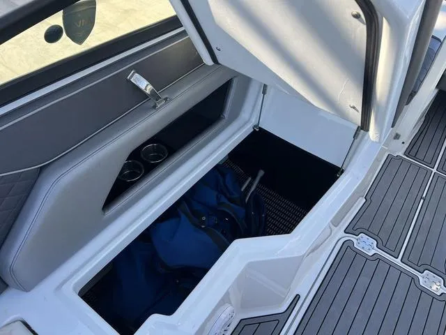 Slide: The Image of Storage compartment in 2020 Monterey MX6 SURF boat with blue bag and cup holders. - 19