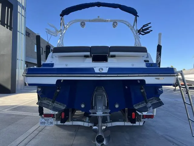 Slide: The Image of 2020 Monterey MX6 SURF boat, rear view, parked outdoors, blue and white design. - 7