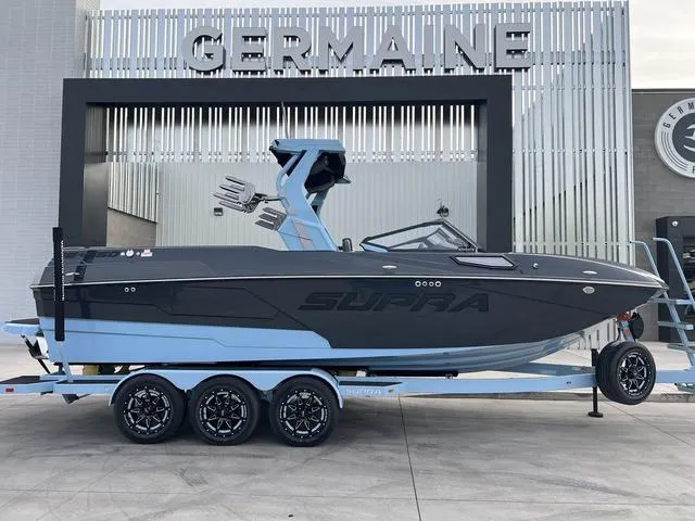 Slide: The Image of 2025 Supra SE 575 boat on trailer at Germaine dealership. - 1