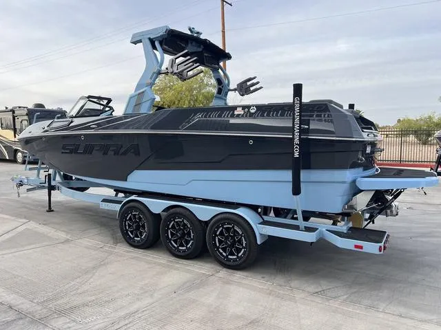 Slide: The Image of 2025 Supra SE 575 boat on trailer, sleek design, black and blue color scheme. - 6