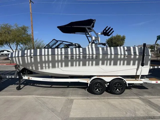 Slide: The Image of 2025 Moomba Max boat on trailer, parked outdoors under striped shadows. - 5