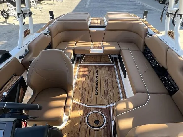 Slide: The Image of 2025 Moomba Max boat interior with tan seating and wood flooring. - 8