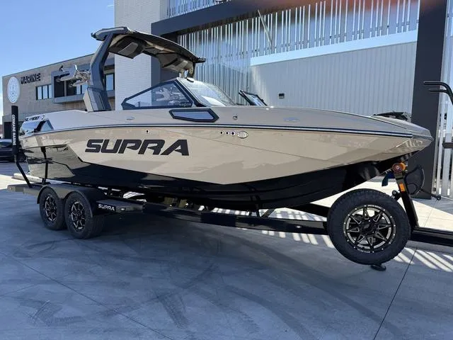 Slide: The Image of 2025 Supra SL 400 boat on trailer, sleek design, parked outdoors. - 2