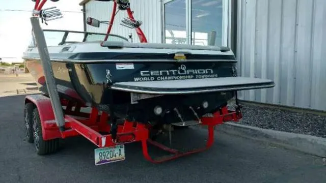 Slide: The Image of 2009 Centurion Elite V C4 Air Warrior boat on red trailer, parked near a building. - 4