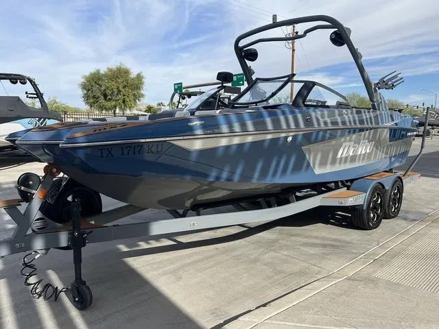 Slide: The Image of 2021 Malibu 23 MXZ boat on trailer, parked outdoors under clear sky. - 4