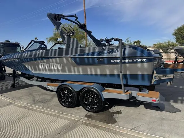 Slide: The Image of 2021 Malibu 23 MXZ boat on trailer, blue and gray, parked outdoors. - 6