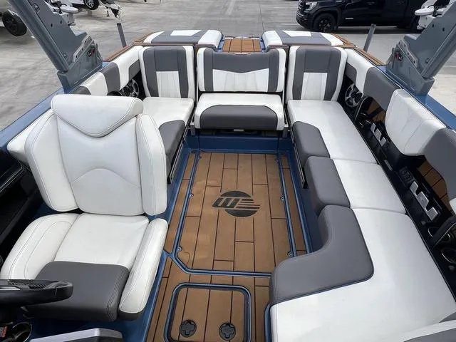 Slide: The Image of 2021 Malibu 23 MXZ boat interior with white and gray seating, wooden flooring. - 8