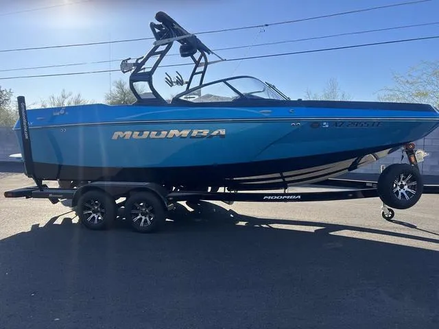 Slide: The Image of 2023 Moomba Max boat on trailer, blue exterior, parked outdoors. - 6