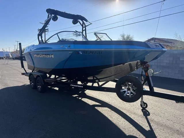 Slide: The Image of 2023 Moomba Max boat on trailer, blue exterior, parked outdoors. - 7