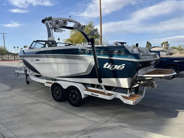 Slide: The Image of 2020 Tigé 25ZX boat on trailer, parked outdoors under a clear sky. - 6