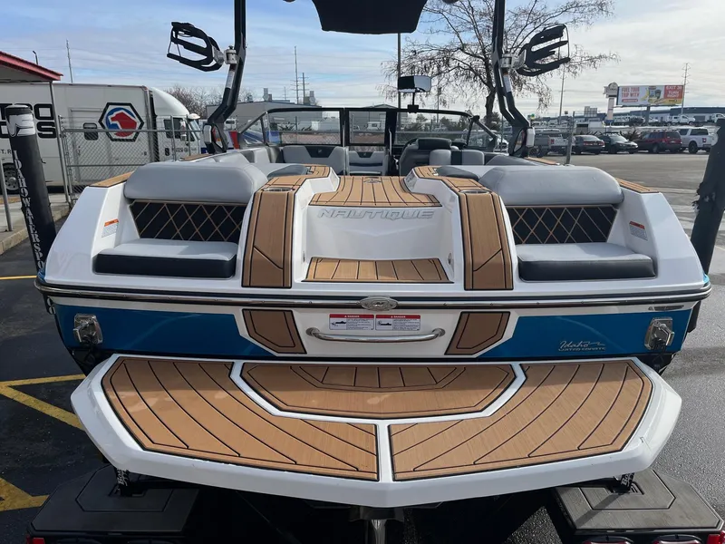 Slide: The Image of 2020 Nautique GS22 boat with teak deck, blue and white exterior, parked outdoors. - 14