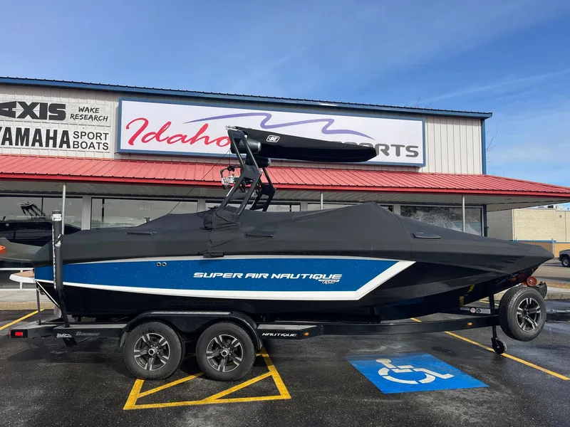 Slide: The Image of 2020 Nautique GS22 boat with cover, parked at Idaho Sports dealership. - 2