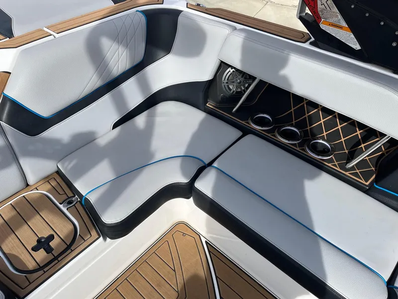 Slide: The Image of 2020 Nautique GS22 interior seating with cup holders and speaker, featuring sleek design and wood accents. - 23