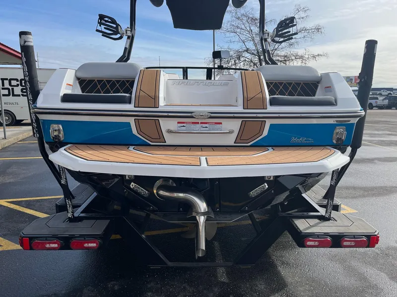 Slide: The Image of 2020 Nautique GS22 boat rear view with teak deck and blue accents. - 5
