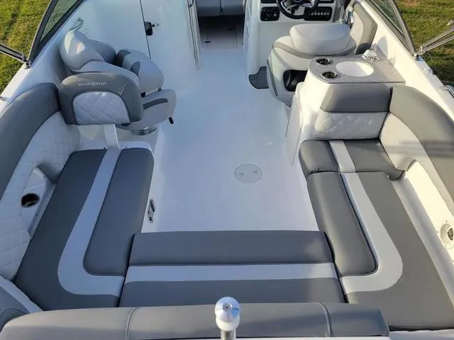 Slide: The Image of 2024 NauticStar 243 DC boat interior with gray and white seating, steering console, and cup holders. - 6