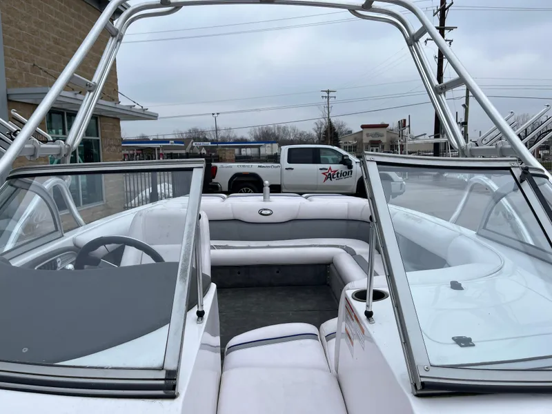 Slide: The Image of 2004 Supra Launch boat interior with seating and windshield, parked near a building. - 17