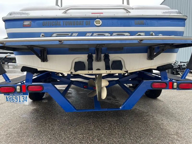 Slide: The Image of 2004 Supra Launch boat on trailer, rear view, Michigan license plate visible. - 7