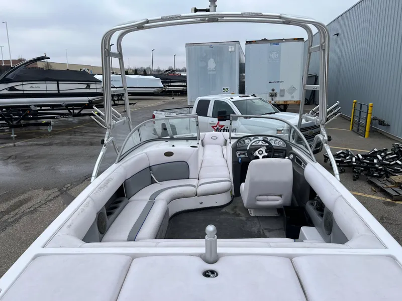 Slide: The Image of 2004 Supra Launch boat interior with white seating and steering wheel, parked outdoors. - 8