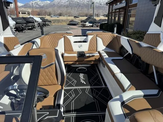 Slide: The Image of 2025 Tigé 24RZX boat interior with luxurious brown and white seating, mountain backdrop. - 11