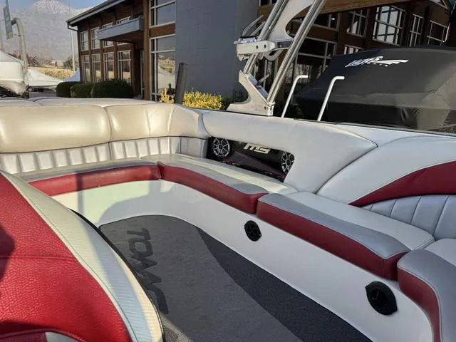 Slide: The Image of 2014 MB SPORTS F24 Tomcat boat interior with red and white seating, docked outdoors. - 16