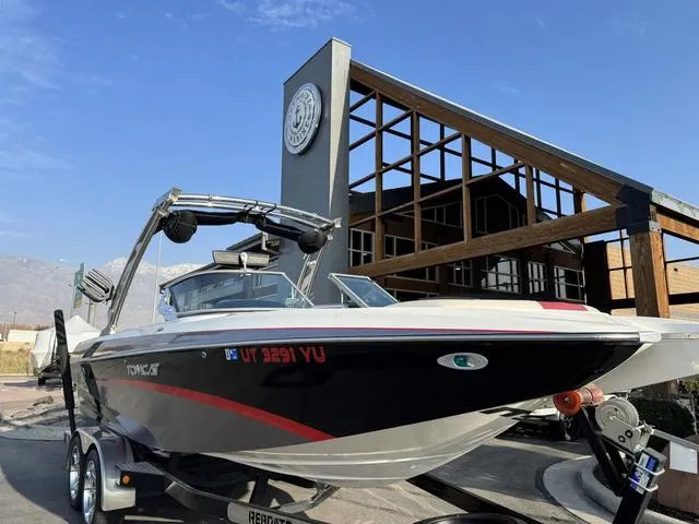 Slide: The Image of 2014 MB SPORTS F24 Tomcat boat on trailer, parked near modern building, clear sky background. - 4