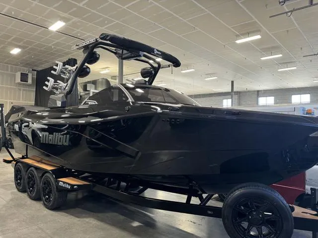 Slide: The Image of 2024 Malibu 26 LSV boat in a showroom, featuring sleek black design and modern amenities. - 12