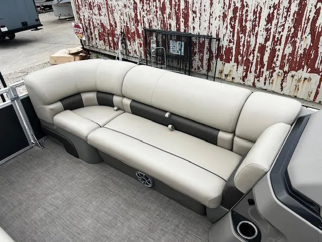 Slide: The Image of 2024 Sun Tracker 20PB pontoon boat with beige seating and rustic background. - 10