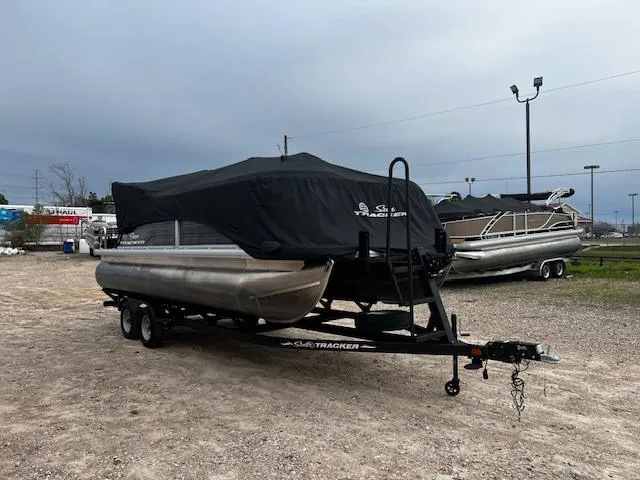 Slide: The Image of 2024 Sun Tracker 20PB pontoon boat on trailer, covered, parked outdoors. - 14