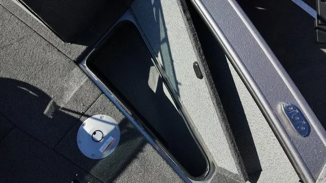 Slide: The Image of 2025 Lund 2075 Fisherman Sport boat interior storage compartment, open hatch, and carpeted floor. - 4