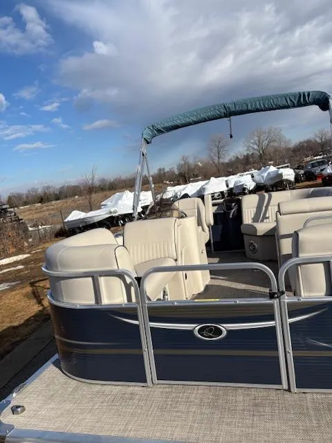 Slide: The Image of 2021 Quest le816 pontoon boat with beige seating and blue canopy under a cloudy sky. - 6