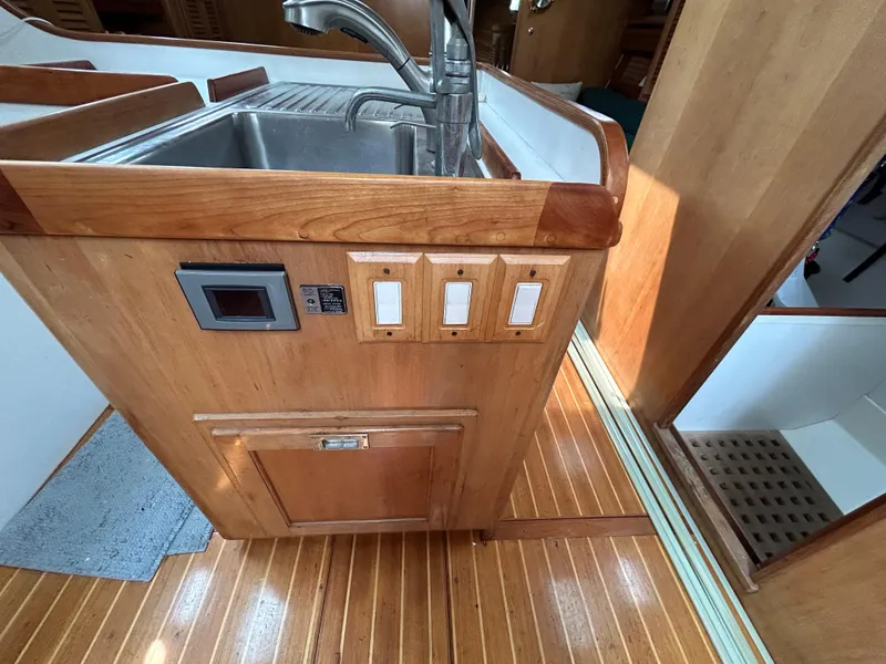 Slide: The Image of 1994 Freedom 45 Aft Cockpit yacht kitchen with wooden cabinetry and stainless steel sink. - 14