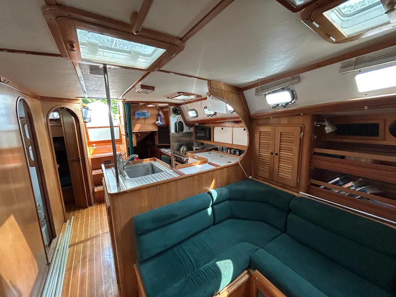 Slide: The Image of 1994 Freedom 45 Aft Cockpit interior with green seating, wooden cabinetry, and ample natural light. - 15