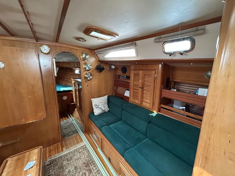 Slide: The Image of 1994 Freedom 45 Aft Cockpit interior with wooden finish, green sofa, and cozy cabin layout. - 19