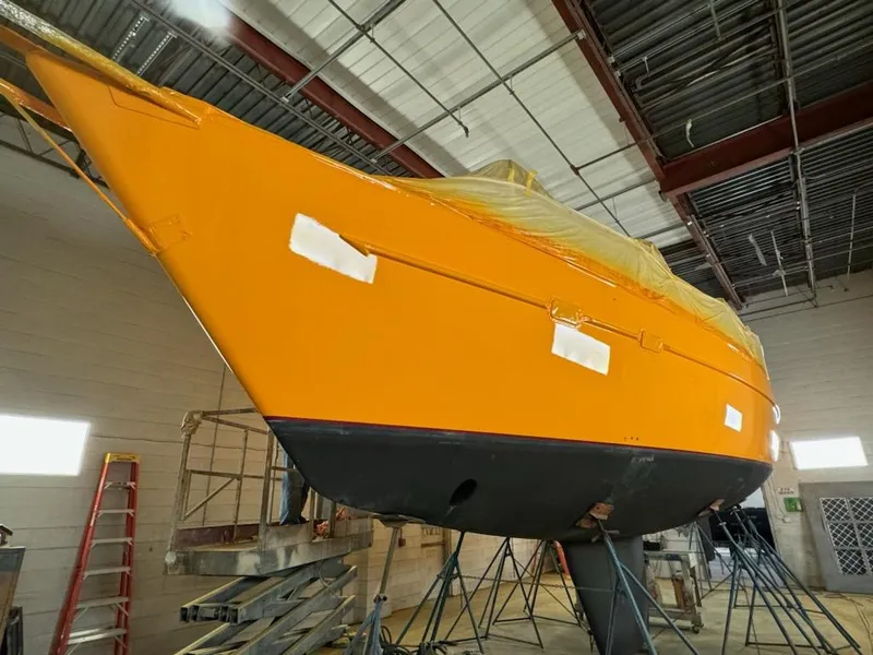 Slide: The Image of 1994 Freedom 45 Aft Cockpit sailboat in a workshop, vibrant orange hull, under maintenance. - 2