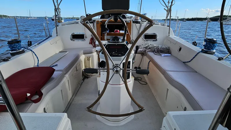 Slide: The Image of 1994 Freedom 45 Aft Cockpit sailboat interior with steering wheel and seating, on calm waters. - 6