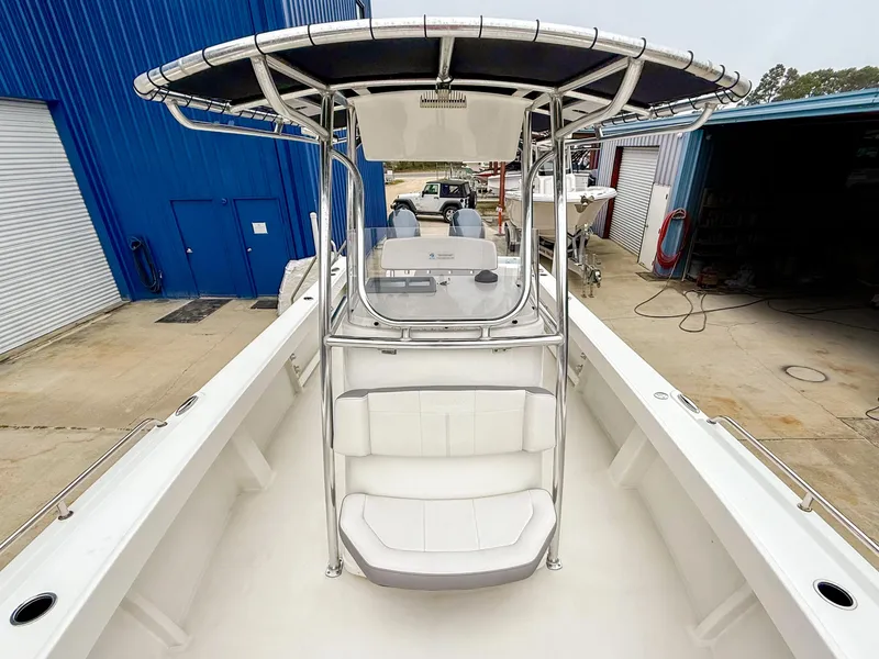 Slide: The Image of 2024 Parker 2501 boat with T-top, docked near blue warehouse. - 10