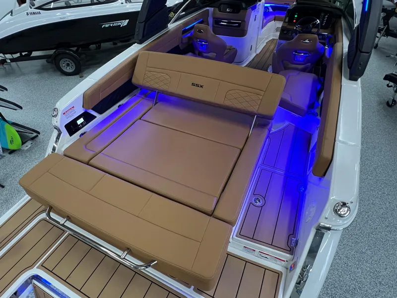 Slide: The Image of 2025 Chaparral 267 SSX boat interior with tan seating and blue LED lighting. - 14