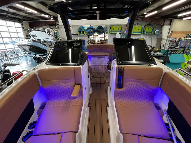 Slide: The Image of 2025 Chaparral 267 SSX boat interior with ambient blue lighting in showroom. - 31