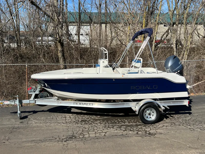 The Image of 2025 Robalo R160 Center Console boat on trailer, parked outdoors. - 0