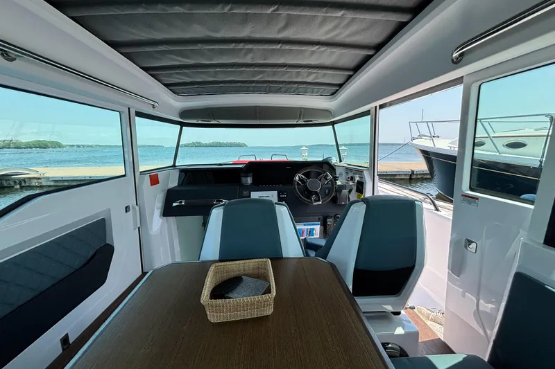 Slide: The Image of Interior of 2022 Axopar 37XC boat with steering wheel and table, docked by the water. - 19