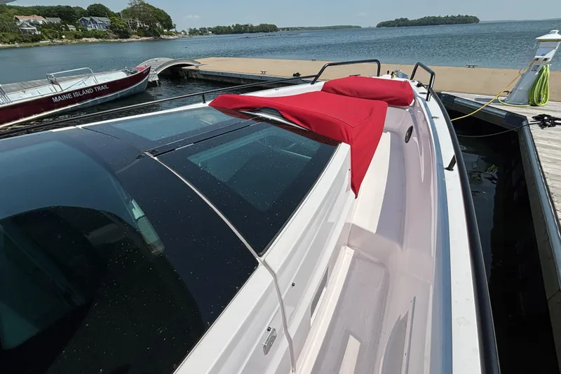 Slide: The Image of 2022 Axopar 37XC boat docked with red cushions, scenic waterfront view. - 32