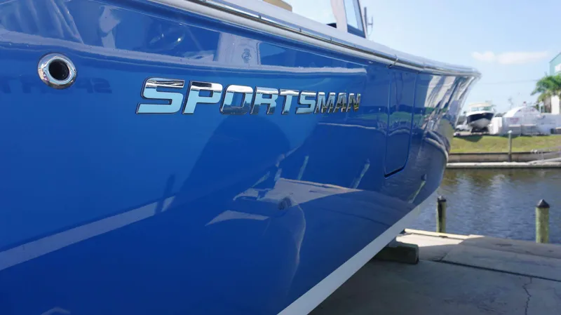 Slide: The Image of 2025 Sportsman 262 Open boat, blue hull, docked near water. - 4
